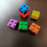 Een aantal gekleurde lego steentjes met een klein magneetje