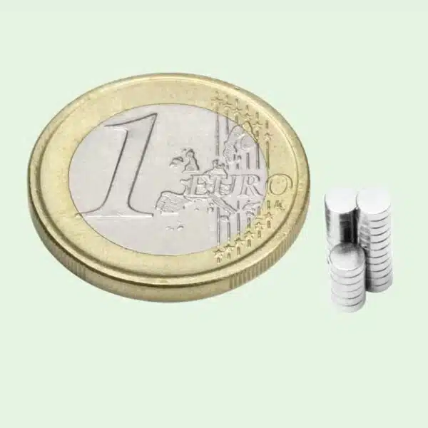 Mini schijfmagneetjes van 3 x 1 op een stapeltje naast een euromunt