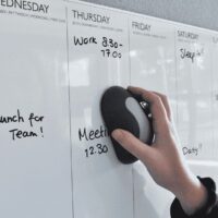 Een whiteboard wordt schoongeveegd met een magnetische whiteboardwisser