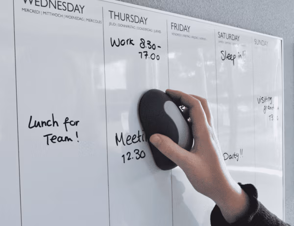 Een whiteboard wordt schoongeveegd met een magnetische whiteboardwisser