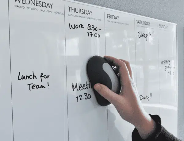 Een whiteboard wordt schoongeveegd met een magnetische whiteboardwisser
