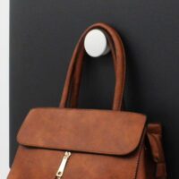 Een handtas die aan een witte magneethaak hangt op een zwart magneetbord
