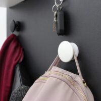 Magneet haken wit Kalamitica magneethaken voor magneetbord in de kleuren wit en zwart en waar kleding en een handtas aan opgehangen zijn