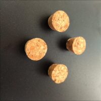 Vier sterke magneten in de vorm van een flessenkurk op een zwart magneetbord