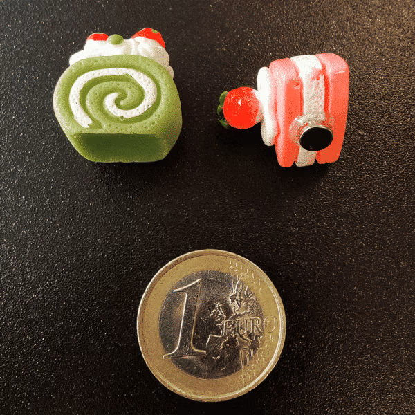 Twee gebakjes van hars met een magneetje aan de achterzijde op een zwart magneetbord geplaatst