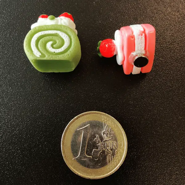 Twee gebakjes van hars met een magneetje aan de achterzijde op een zwart magneetbord geplaatst