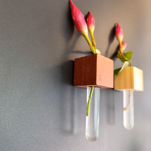 Twee muurvaasjes met een bloem op een zwart magneetbord